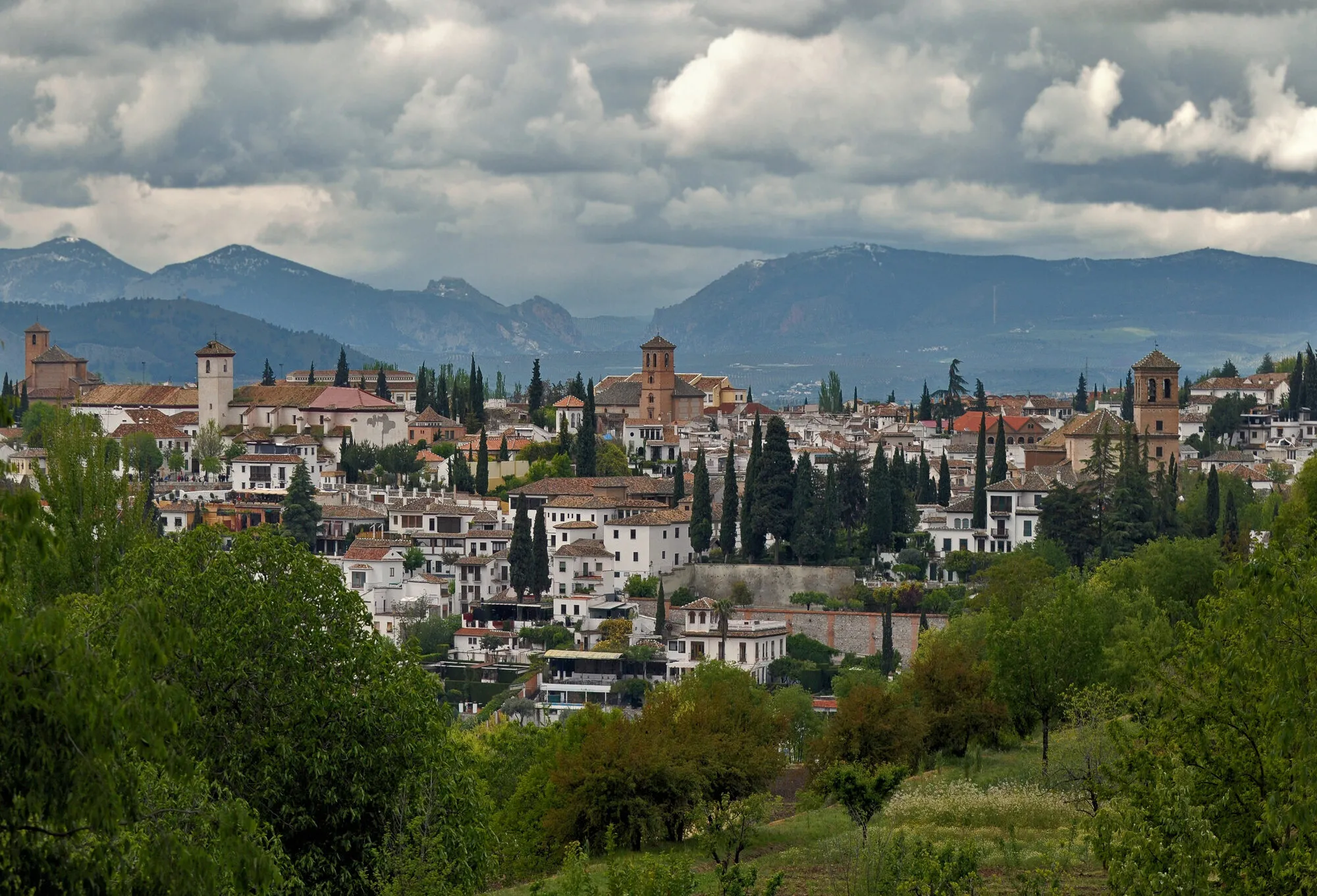 Whitewashed houses of Granada's Albaicin quarter climbing the hillside, seen from the Alhambra