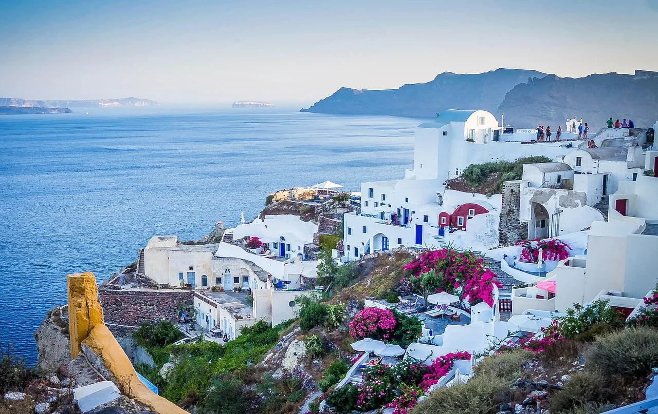 The white cliffside houses and blue-domed rooftops of Oia in Santorini, Greece, above the caldera