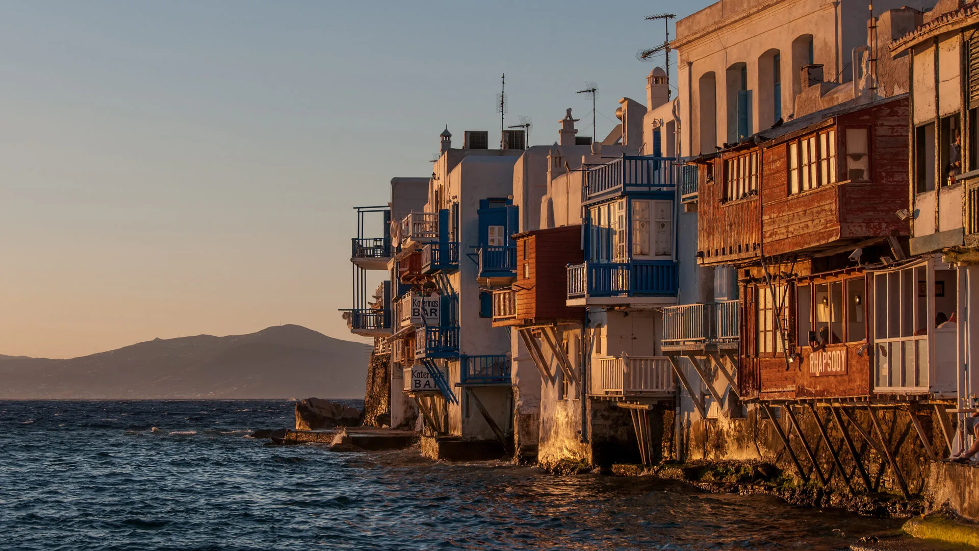The waterfront bars and wooden balconies of Little Venice in Mykonos at sunset