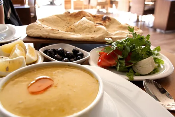 A Turkish mezze table with hummus, flatbread, black olives, tomato and onion