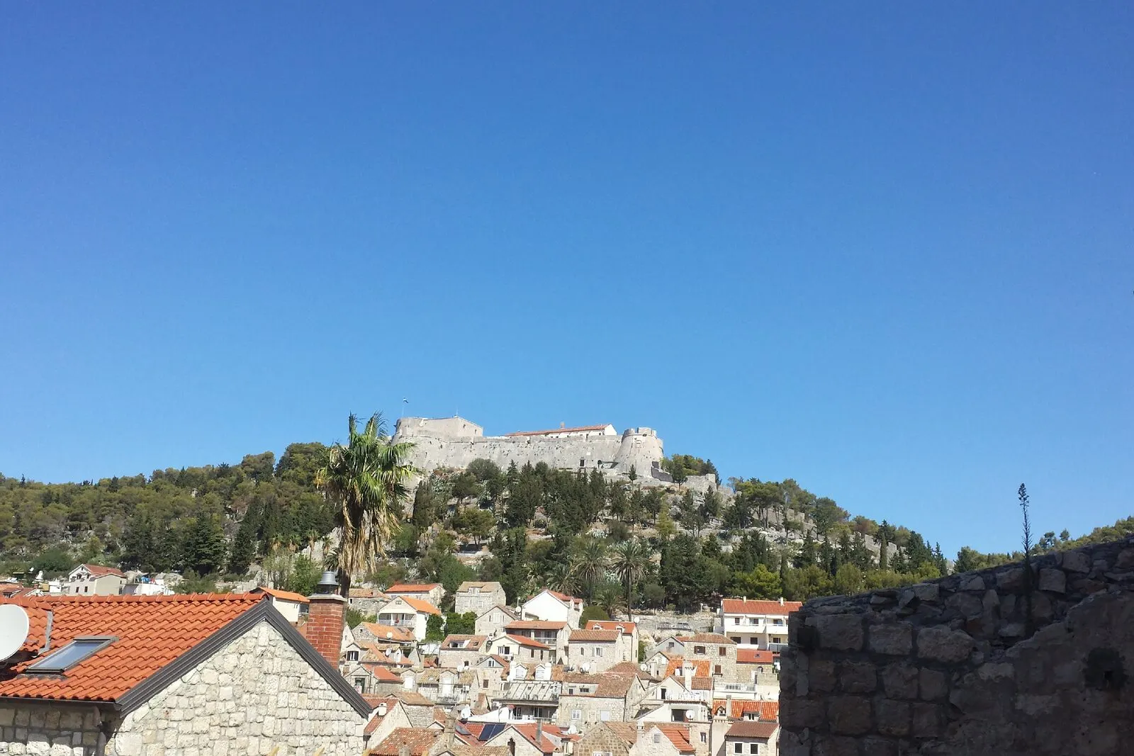 The rooftops of Hvar town with the Fortica fortress on the hill above