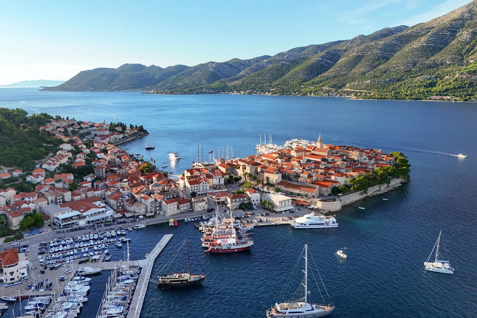 An aerial view of Korcula old town on its peninsula, with the harbour and mountains behind