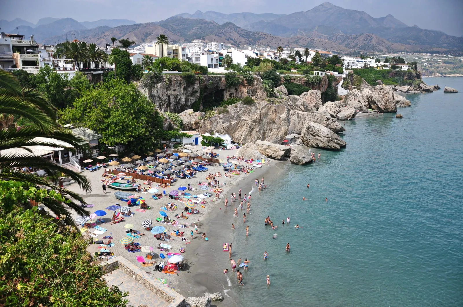 The beach and cliffs of Playa de Calahonda in Nerja, with white houses and mountains above the sea
