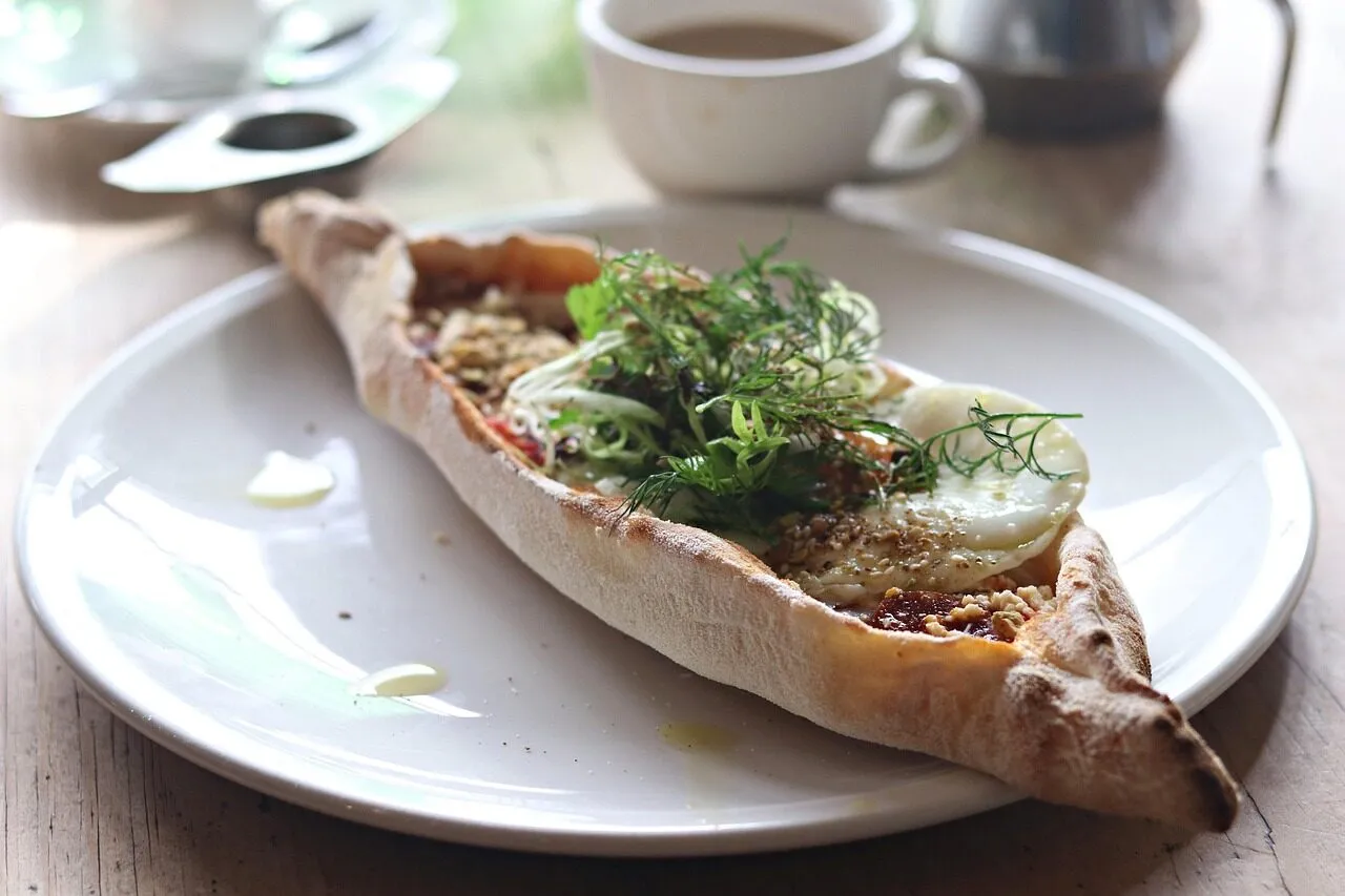A boat-shaped Turkish pide flatbread topped with meat and fresh herbs